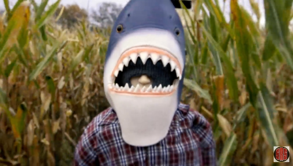 En mand står i en kornåge iført en hajmaske i den lav-budget gyserfilm Sharks of the Corn.